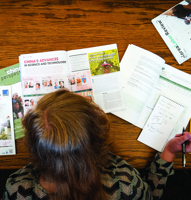 Top-down view of a student reviewing and taking notes on Asian periodicals