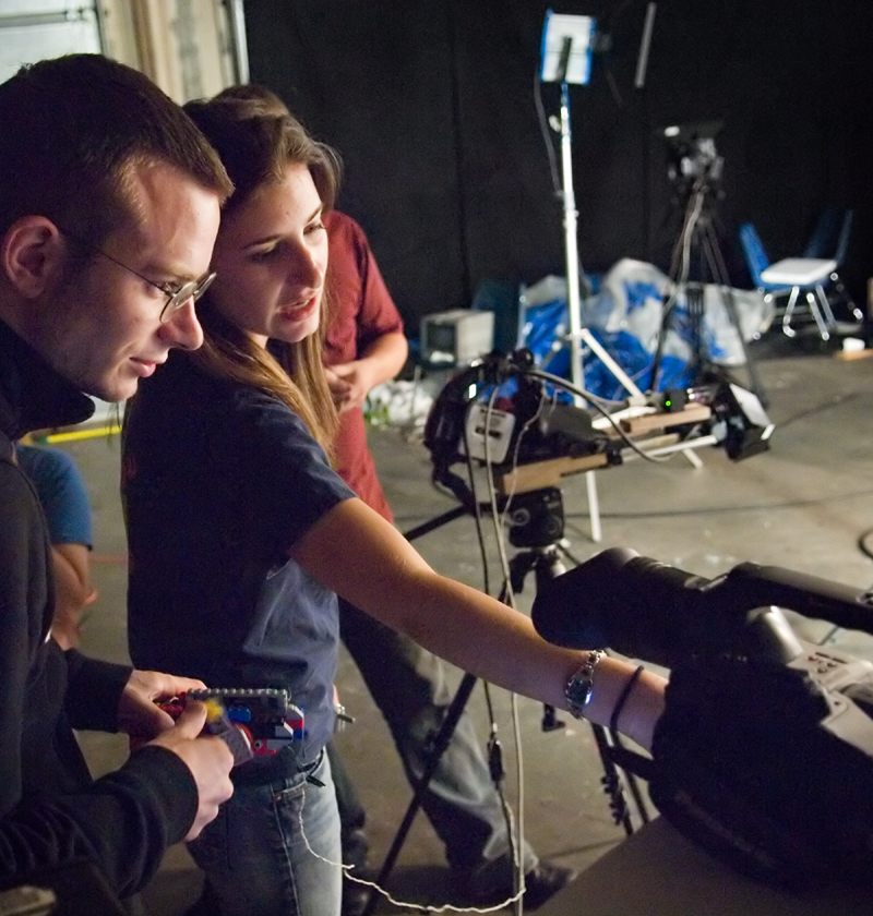 Two people behind a film camera discuss what they see on the display.