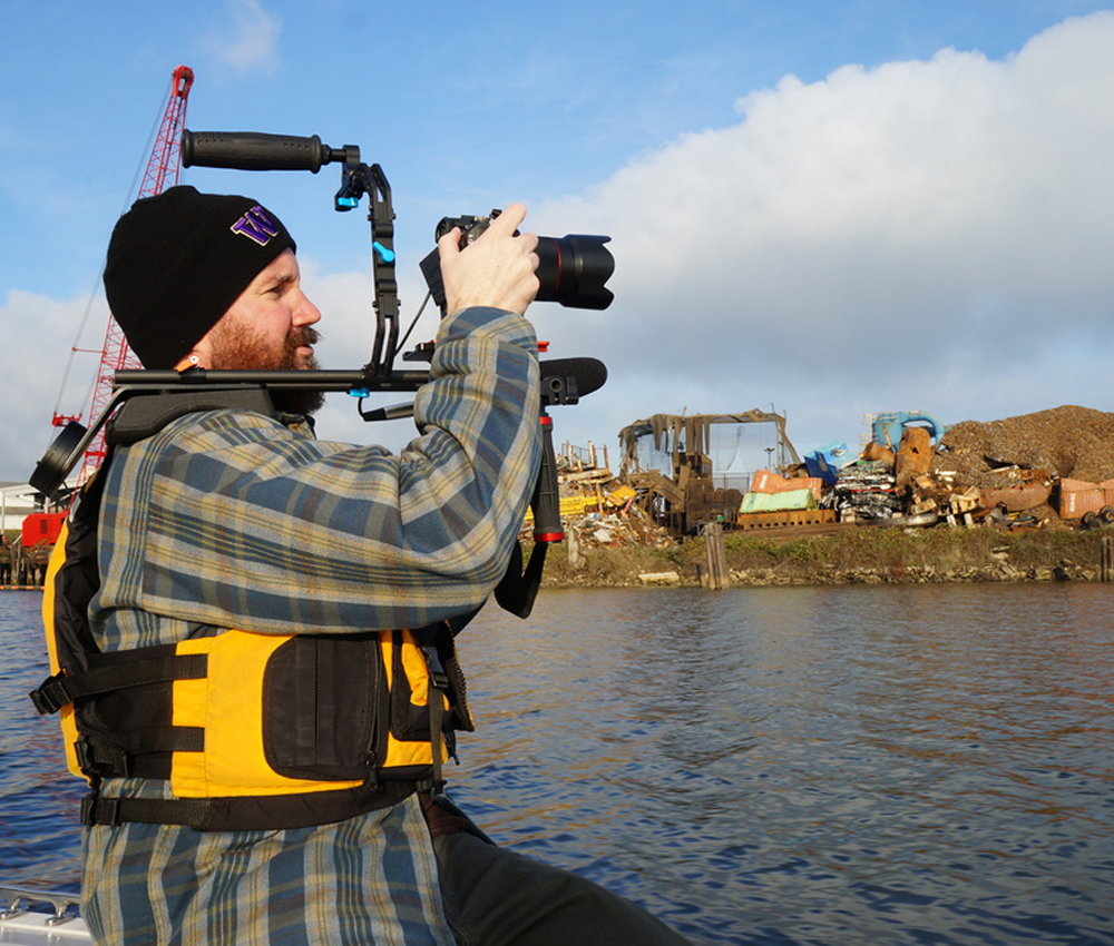 Person looks through a camera over a river.