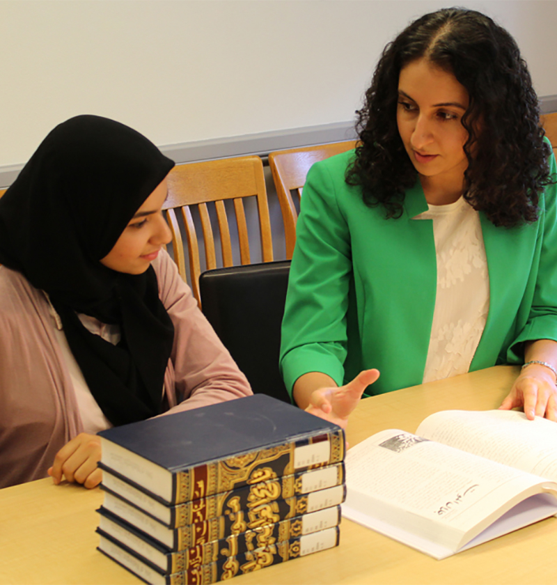 Professor talking with a student at a table.