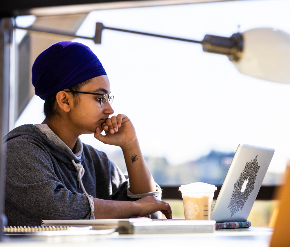 A student is working on a laptop seated at a desk.