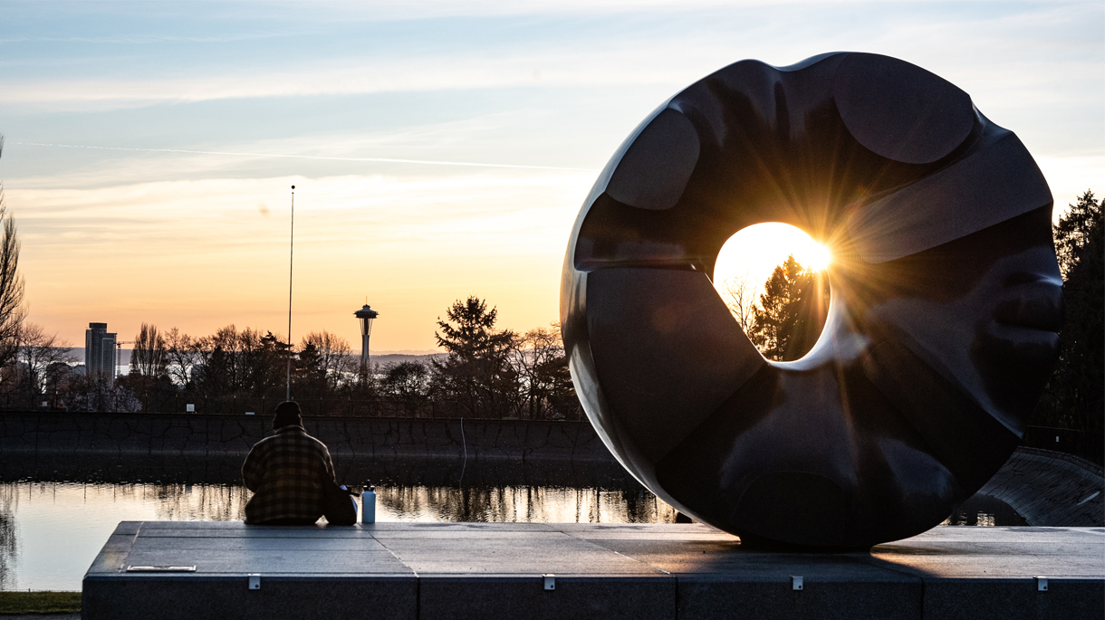 Sunset backlights Isamu Noguchi's "Black Sun" sculpture and the Space Needle at Volunteer Park in Capitol Hill, Seattle.