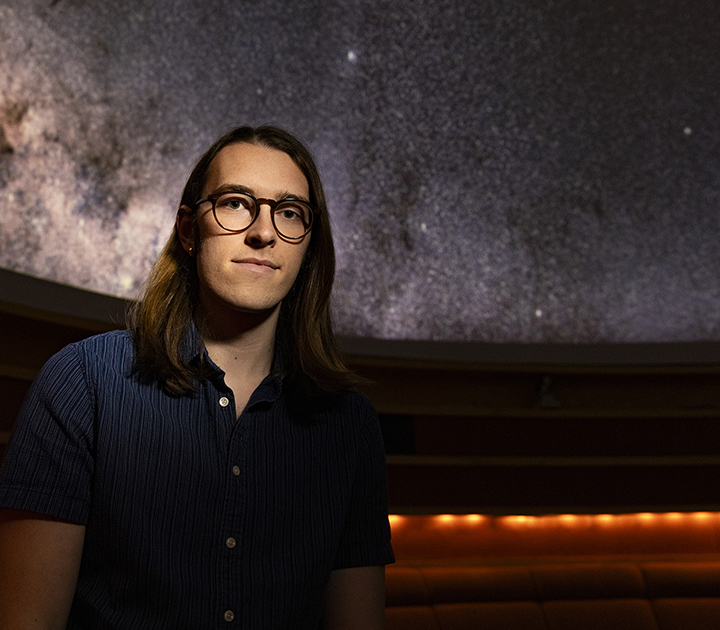 Max Frissell in the UW Planetarium, with the starry "sky" visible behind him.